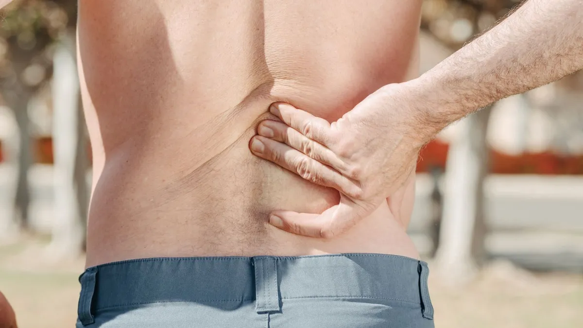 Homem com a mão nas costas sentindo dor muscular