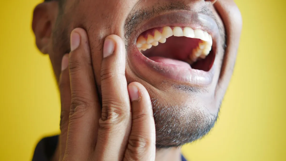 Homem com a mão no rosto sentindo dor na boca