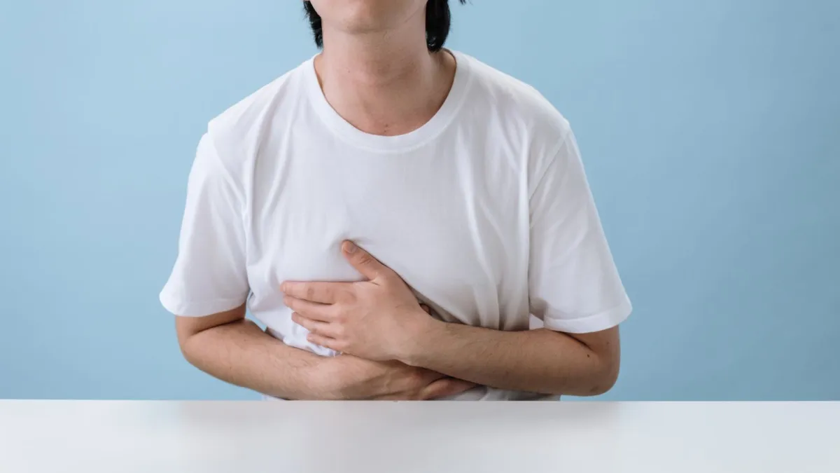 Homem com a mão no estômago sentindo azia e queimação