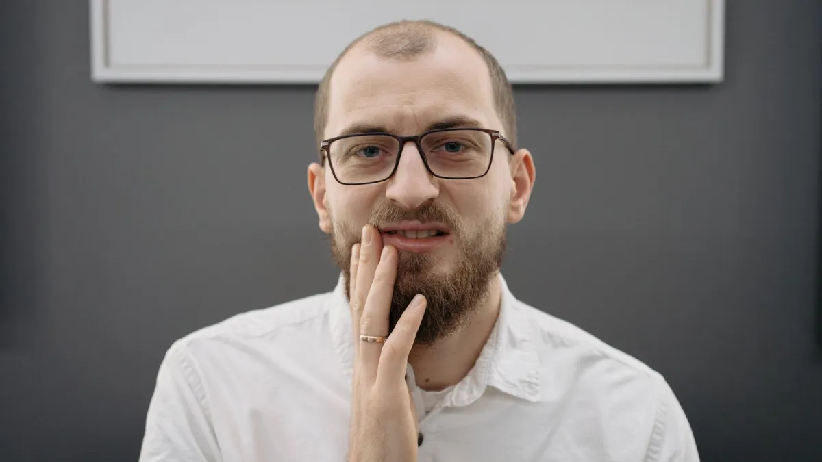 Homem de óculos segurando o rosto com dor de dente