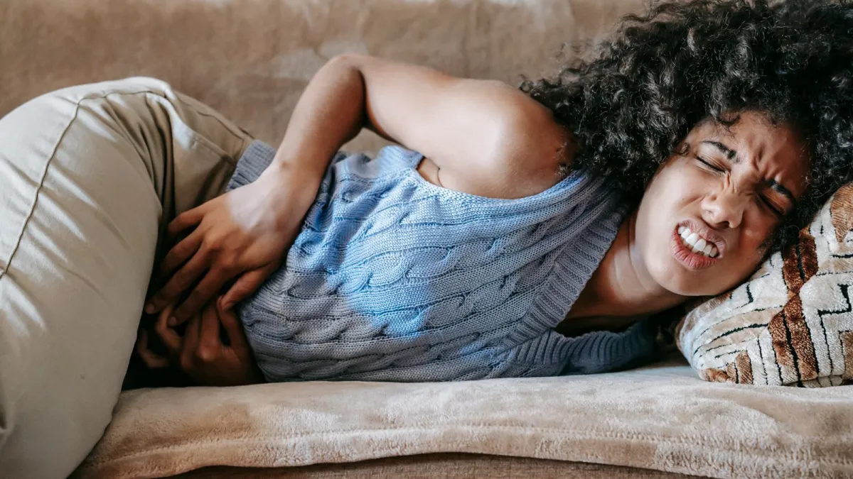 Mulher deitada no sofá com dor de estômago