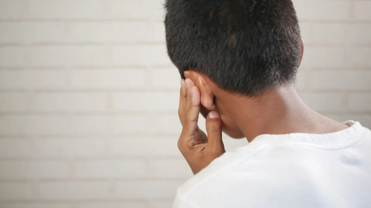 Criança com a mão no ouvido por causa de dor de ouvido